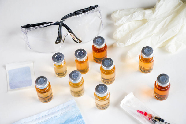 Vacina em ampolas e garrafas, agulha, luva e vidro de segurança. - Foto, Imagem