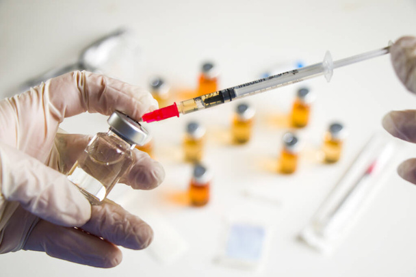 Vírus da Corona e Covid - 19 nova vacina em ampolas e frascos, agulha e mãos de médicos com luva. - Foto, Imagem