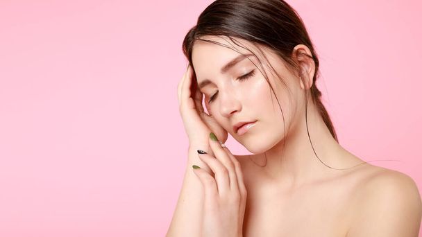 beauty, skin care and people concept - Beauty fashion model girl natural makeup with cute smile on pink background. woman touching her face with her hands. 16:9 panoramic format. - Fotografie, Obrázek