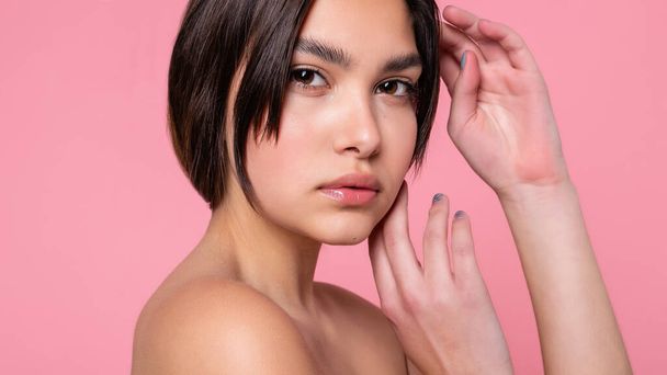 Close up face of beautiful young woman with clean perfect skin. Portrait of beauty model with natural nude make up. Spa, skin care and wellness. Pink peach coral background. 16:9 panoramic format. - Fotografie, Obrázek