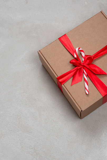 Craft colored christmas gift box with red ribbon on concrete background - Foto, Imagen
