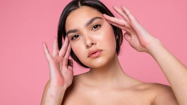 Close up face of beautiful young woman with clean perfect skin. Portrait of beauty model with natural nude make up. Spa, skin care and wellness. Pink peach coral background. 16:9 panoramic format. - Фото, изображение