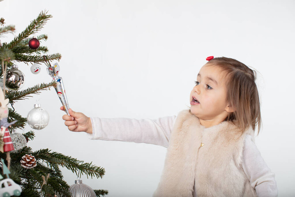 Douce petite fille essayant d'obtenir des bonbons du sapin de Noël - Photo, image