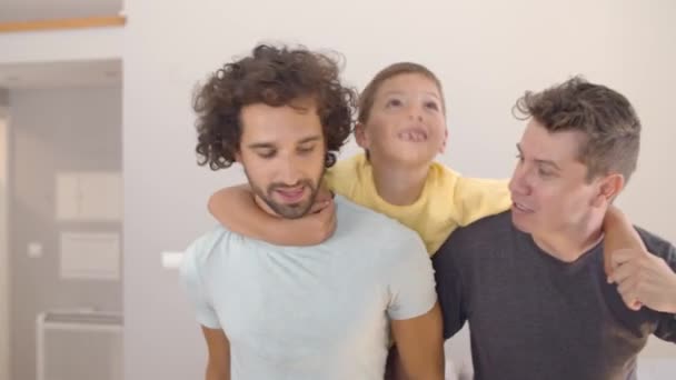 Happy kid i jego dwóch ojców korzystających z aktywności w domu - Materiał filmowy, wideo