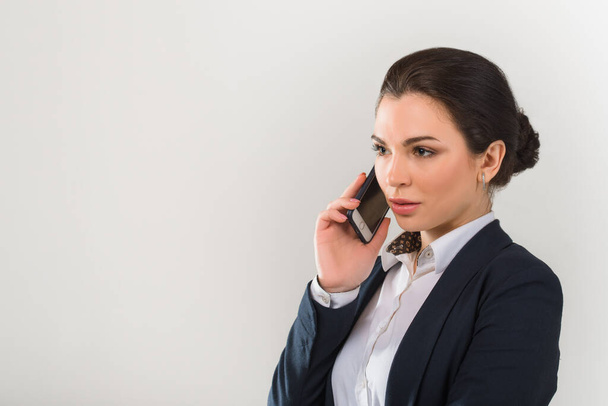 Портрет серьезной симпатичной деловой женщины, разговаривающей по телефону в современном офисе - Фото, изображение