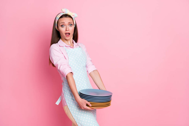 Portrait of astonished wife girl hold many pile stack dirty dishes impressed wear dotted shirt isolated over pastel color background - Photo, Image