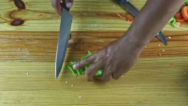 ylhäältä näkymä miehen kädet leikataan veitsellä kappaletta suuri vihreä pippuri viipaleita - Materiaali, video