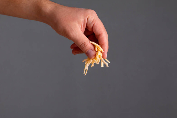 Primer plano del hombre mano espolvorear queso rallado sobre fondo oscuro - Foto, imagen