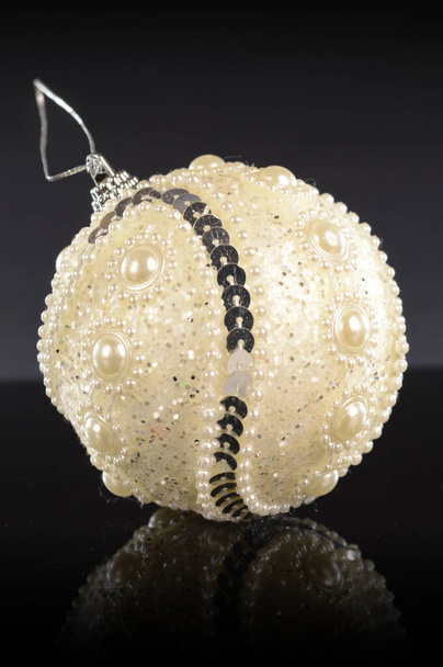 A closeup vertical composition of a white festive holiday bauble for tree decorating during the Christmas season. - Foto, Imagem