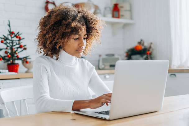 Темнокожая девушка смотрит в ноутбук и любит онлайн-покупки - Фото, изображение