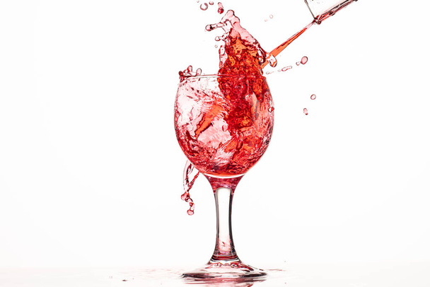 splash and flow of red wine in a glass on a white background with reflection - Foto, Bild
