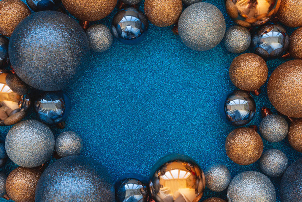 Blue and golden Christmas baubles decoration on blue glittering background. Top view. Copy space. New Year or Christmas - Φωτογραφία, εικόνα