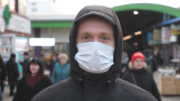 A városi utcában áll egy arcmaszkos fiatalember portréja. Egy fickó, aki védőmaszkot visel a kinti vírusoktól a tömegben. Az egészségi és biztonsági élet koncepciója a coronavirus pandémiától - Felvétel, videó