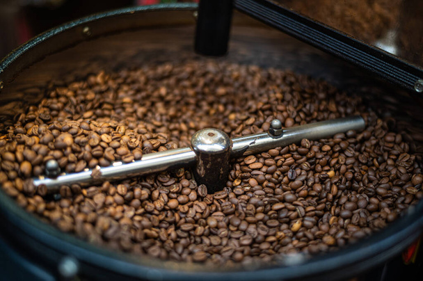 冷却プレート上の茶色のコーヒー豆の混合と焙煎-仕事中のプロのコーヒーロースターマシン. - 写真・画像
