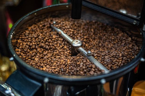 Proces zbliżeniowy pieczenia świeżej smażonej ziarna kawy. Przetworzone ziarna kawy są mieszane wokół płyty chłodzącej piekarnik - Zdjęcie, obraz
