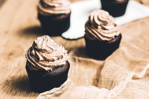 Muffin al cioccolato con crema su fondo di legno. Muffin fatti in casa. Dolce. - Foto, immagini