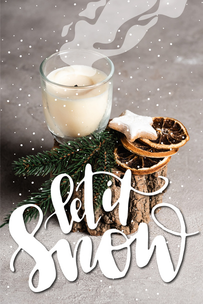 Scented candle with pine brunch, dried orange slices and cookie on wooden stand near let is snow lettering  - Foto, Imagem