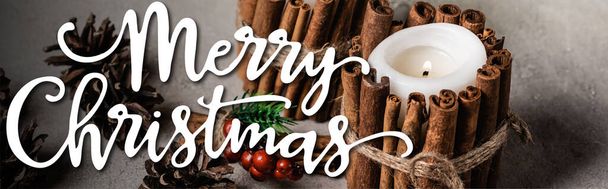decorated candles with cinnamon sticks near pine cones and merry christmas lettering, banner - Photo, Image