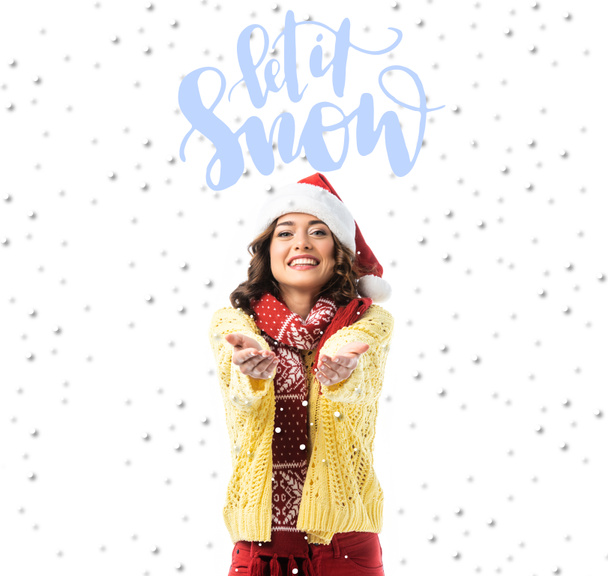 örömteli fiatal nő télapó kalap és sál áll kinyújtott kézzel közel hagyja, hogy hó felirat fehér - Fotó, kép