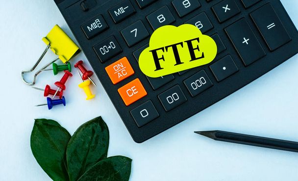 FTE (Full-Time Equivalent) - word on yellow note sheet on white background with calculator, pencil, green sheet and paper clips - Foto, Bild