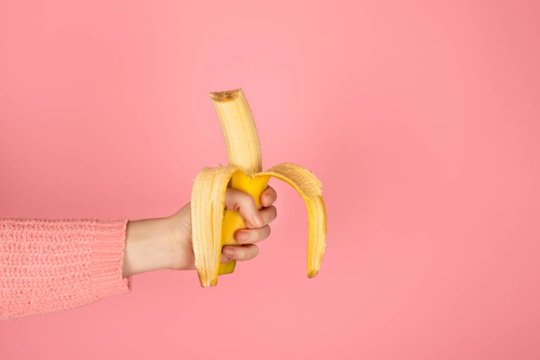 Ženská ruka drží jasně žlutý kousnutý banán. Módní monochromatický proužek s kopírovacím prostorem - Fotografie, Obrázek