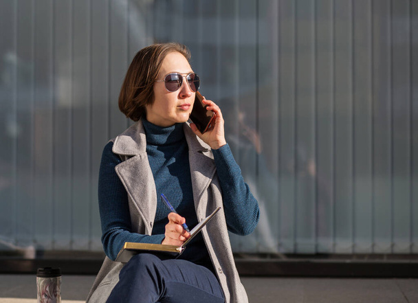 femme d'affaires avec ordinateur portable et téléphone assis dans la ville d'automne - Photo, image
