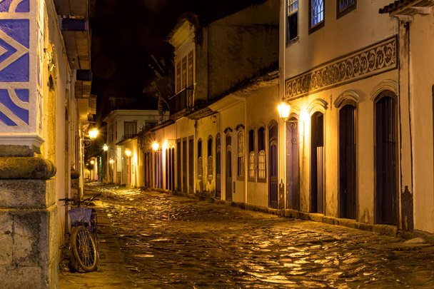 Widok nocny miasta Paraty z jego starych kolonialnych domów stylu i jasności i kolorów światła miasta odzwierciedlone w brukowanych ulicach - Zdjęcie, obraz