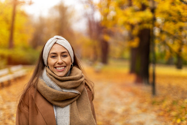 Portrait of smiling young woman in a park in autumn - 写真・画像