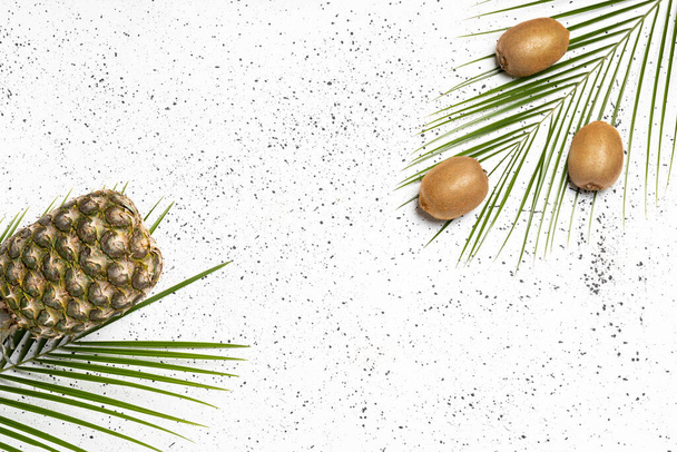 Fresh tropic fruits green kiwi, pineapples on palm tree leaf on white background. Top view, flat lay - Valokuva, kuva