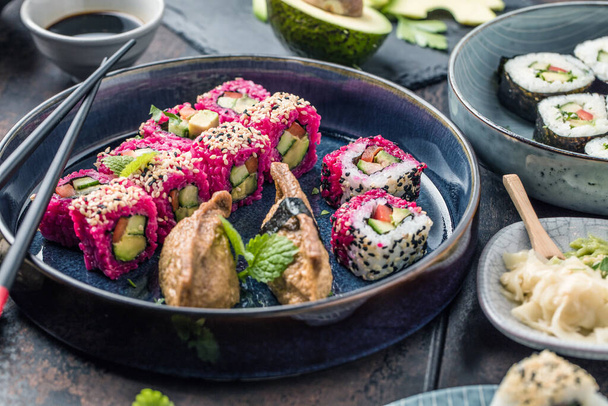 delicious rolls, sushi and maki on a dark wooden board with chopsticks  - Фото, изображение
