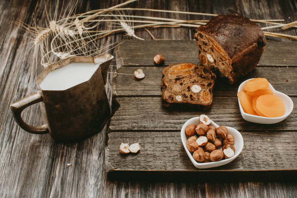 a mug of milk and bread with dried fruit on top  - Photo, image