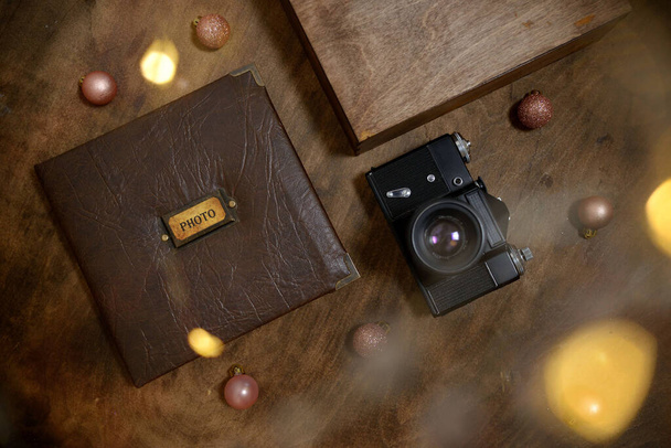 Lahjakirja nahkakannessa puisessa vanerilaatikossa, jossa on vintage-musta kamera. Vintage valokuva-albumi. Semeinfe-valokuvia yhden henkilön elämästä. käsite joulun läsnä perheelle. - Valokuva, kuva