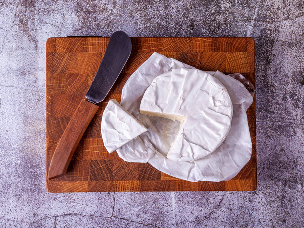 Brie cheese on a wooden cutting board - Foto, afbeelding