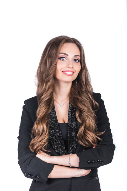 A beautiful woman in a black business suit with a make-up and long hair stands on a white isolated background in the studio. Working and business woman concept - Foto, imagen