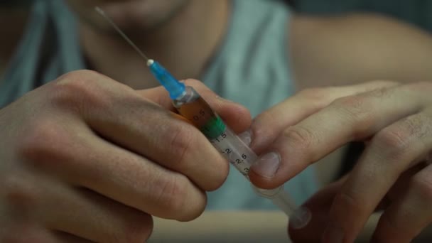 Ένας άντρας που κρατάει μια σύριγγα με ένα φάρμακο στα χέρια του. έννοια εθισμού - Πλάνα, βίντεο