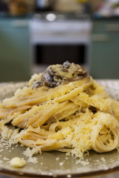 Hausgemachte Pasta mit Pilzen und Käse. Heimische Küche ist im Hintergrund.  - Foto, Bild