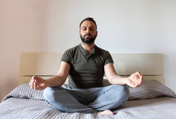 Man meditating on bed at home. Zen concept - Foto, afbeelding