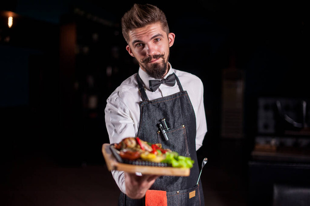 Professional friendly waiter helpfully serves appetizing dish at a festive event. - Photo, Image