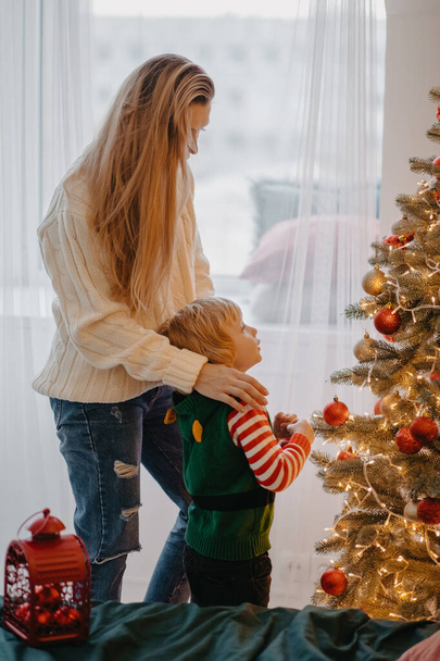 Vánoční nápad. Šťastná matka a roztomilý malý syn zdobení vánoční stromeček spolu - Fotografie, Obrázek