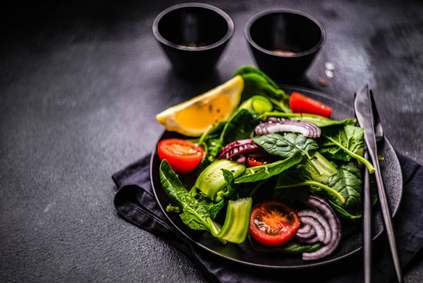 Salade d'aliments sains avec des feuilles d'épinards frais bio avec des graines de sésame servies dans un bol sur fond de béton avec espace de copie - Photo, image