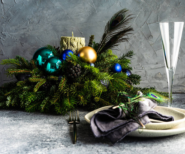 Festive table setting decorated with peacock feather for Christmas dinner on stone background with copy space - Photo, image