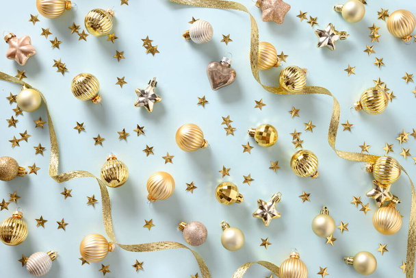 Christmas pattern of golden decorations and festive balls on blue. Top view. Xmas greeting card for wishes. - Фото, зображення