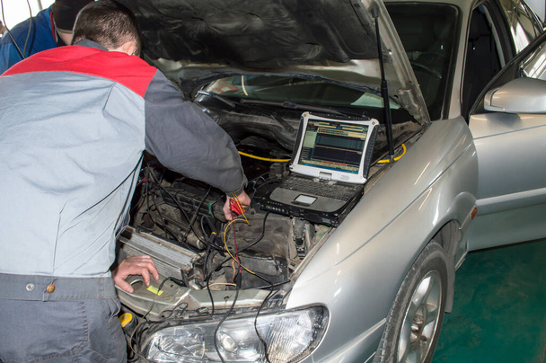 Un automobiliste et un électricien diagnostiquent une voiture à l'aide d'un oscilloscope électronique sur un ordinateur portable dans un atelier de réparation automobile - Photo, image
