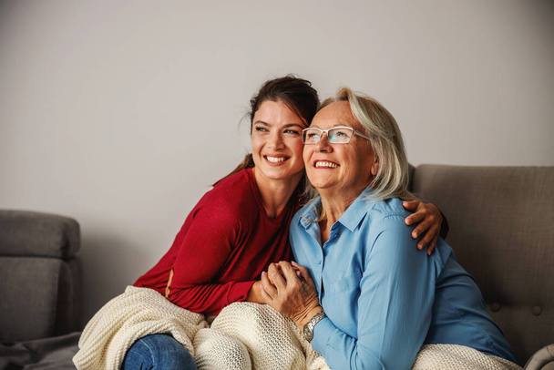 Senior woman and her daughter sitting at home and hugging. - Φωτογραφία, εικόνα