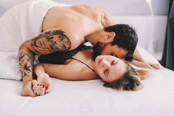 Joven atractiva pareja caucásica haciendo el amor en el dormitorio. - Foto, Imagen