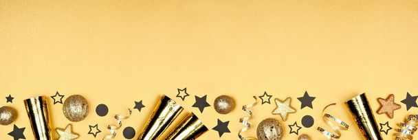 Новый год канун нижней границы блестящих звезд, ленты, украшения и шумоподавителей. Вид сверху на золотой фон шампанского. - Фото, изображение