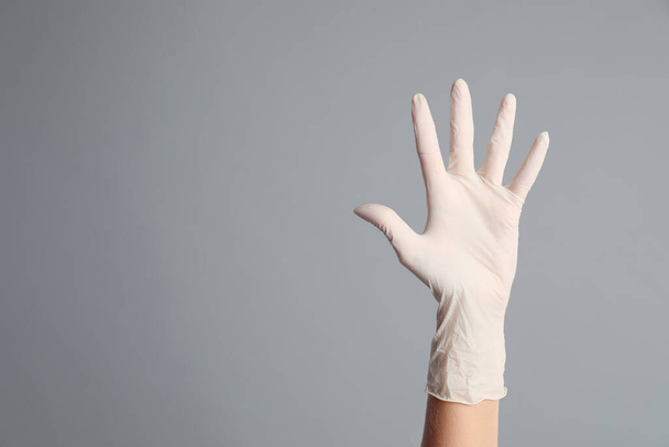 Doctor wearing medical gloves on grey background, closeup. Space for text - Zdjęcie, obraz