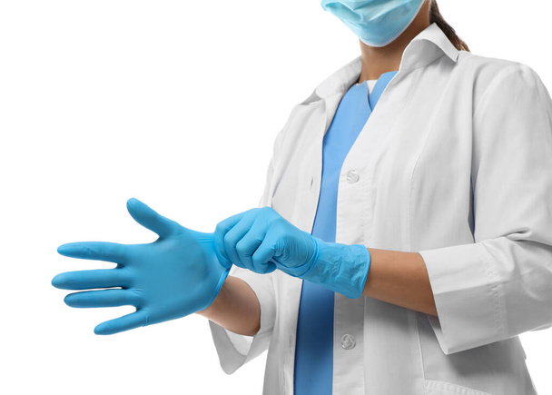 Doctor in protective mask putting on medical gloves against white background, closeup - Fotografie, Obrázek
