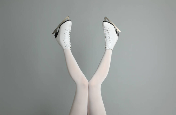 Woman in elegant white ice skates on grey background, closeup of legs - Fotografie, Obrázek