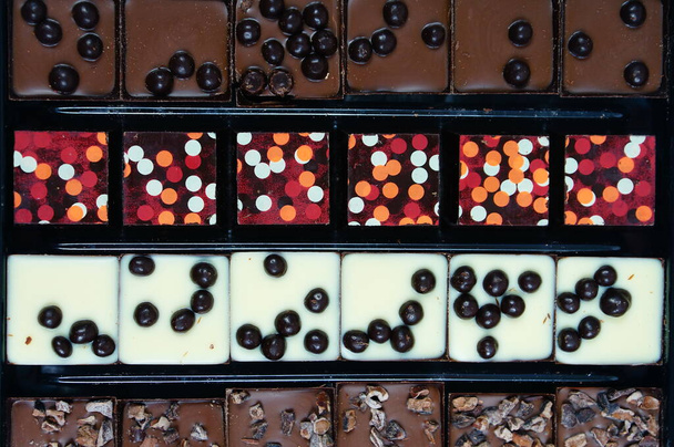 Chocolat aux bonbons - un ensemble élégant de chocolats de dessert, saupoudré de boules de glaçage douces et colorées. - Photo, image